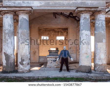 man in ghost costume with skeleton white face. Halloween at cult site of Mortuary. Ancient ruined building. Rites of Samhain, All Saints, Feast of Dead. Natural effects of oncoming sunlight lens glare
