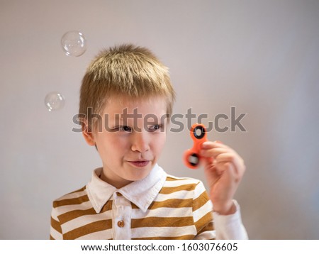 Funny blond child in striped shirt twists spinner on his nose. 4K