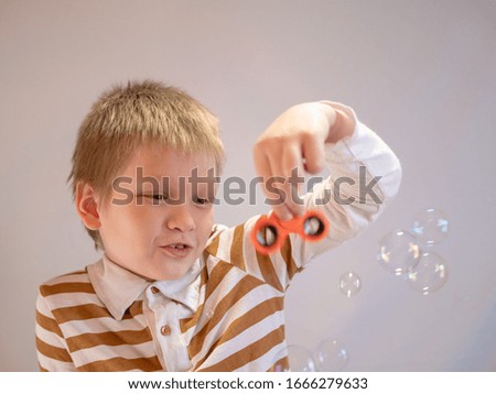 Funny blond child in striped shirt twists spinner on his nose. 4K