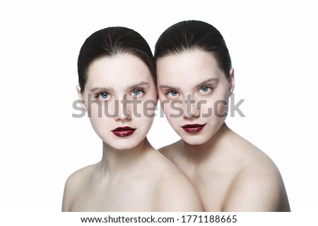 Portrait of two young beautiful girls with clean eye makeup and dark red lipstick
