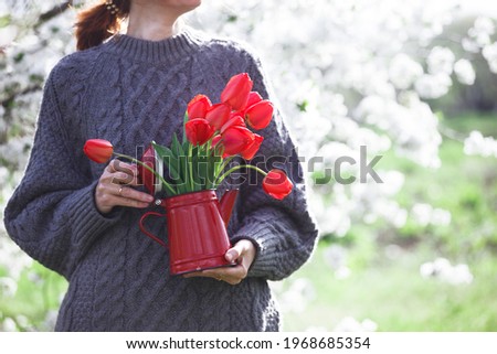 girl holding a teapot with a bouquet of red tulips in her hands