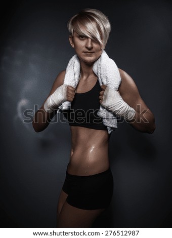 Sweaty woman with towel after training on dark gray background. Hard sporty girl 