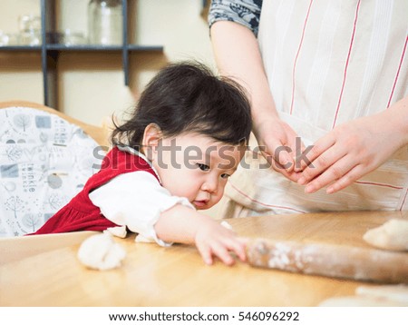 Adorable baby girl making gyoza with mom