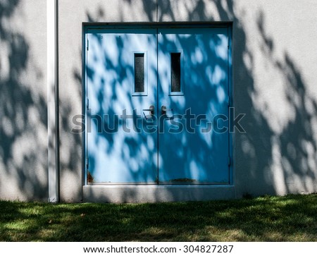 Abstract blue door. Shadows on building. Abstract art. Abstract design. Minimal art and design. Double door. Architecture details. Building entrance exit. Exterior design.