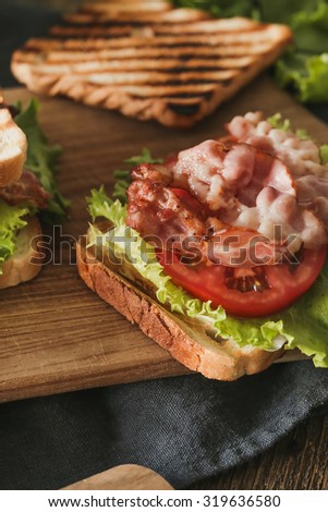 Bacon, lettuce and tomato (BLT) toast  sandwich on wood background
