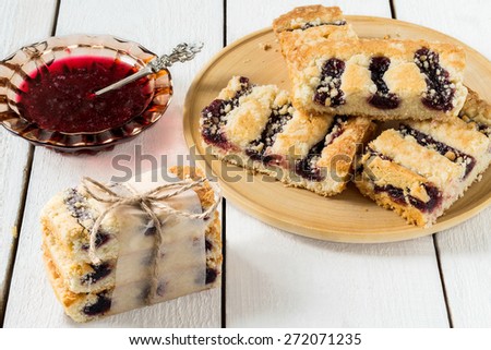 Cake with blueberry jam on a wooden plate, jam in a saucer, slices of cake, tied a tourniquet