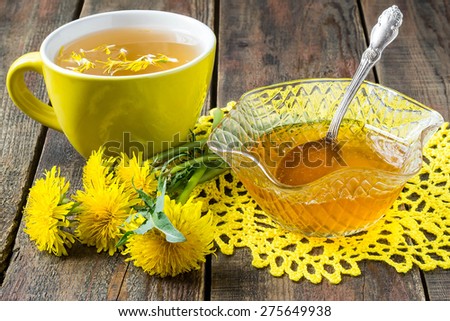 Spring jam of dandelions, flower tea in a yellow cup and a flowers dandelion  on a yellow knitted napkin. Selective focus