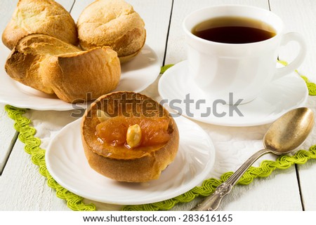 Yorkshire pudding with homemade apple jam, a cup of tea, a plate of pastries on white wooden table. Selective focus