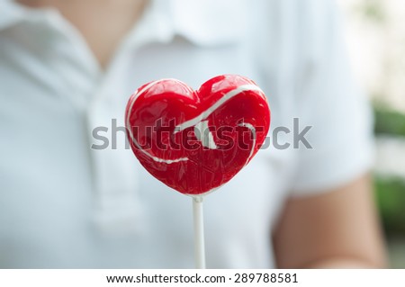 girl is showing big heart shape lollipop