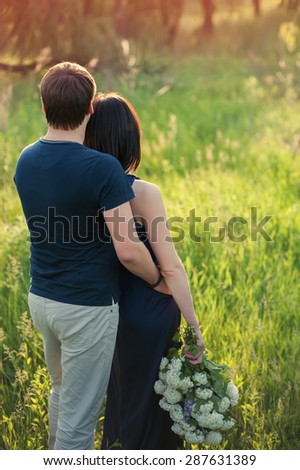 Young loving couple standing in the back with a large bouquet of flowers, love, lifestyle