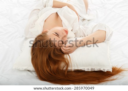 Portrait of a beautiful sexy girl lying on the back in bed in a man\'s shirt