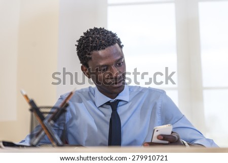 African American businessman at desk using smartphone in the office