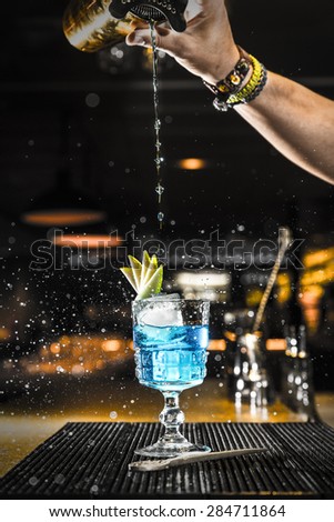 Barman pouring a cocktail into a glass at night club
