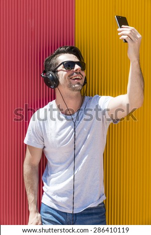 Attractive man with headphones makes selfie photo with his mobile phone