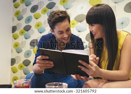 Happy couple watching social media in a notebook at bar. they are studying or working.
