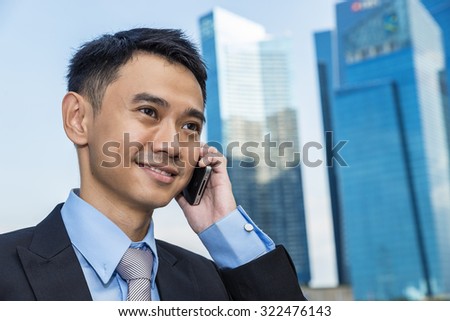 handsome business man speaking mobile phone at his company office building, model is a asian male