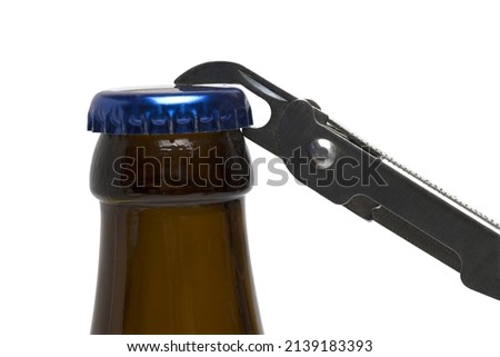 Close up of brown beer bottle with blue crown cork and bottle opener attached to jack knife on white background ストックフォト © 