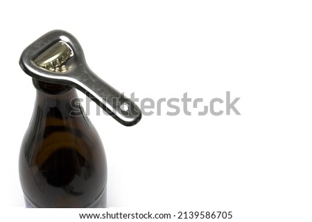 Close up ego view of silver retro vintage bottle opener on crown cap of a brown beer bottle on white background as concept for opening of beverages ストックフォト © 
