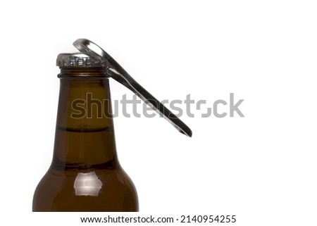 Close up brown glass beer bottle with silver retro vintage bottle opener that opens the crown cap on white background ストックフォト © 