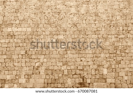 the textured fragment of old stone wall of ancient fortress of sepia color for background