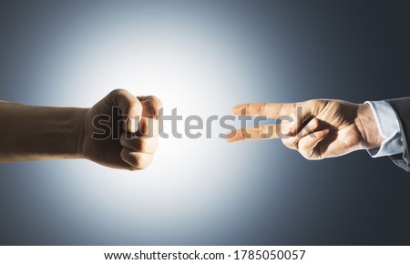 Two hands fist and victory sign on gray background. Business and challenge concept.