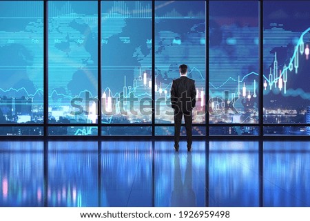 Business investment concept with digital screen on window with stock market chart and businessman looking at night city. Double exposure