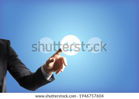 Businessman hand touches the good emoticon, blue background, feedback concept