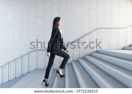 Road to success concept with businesswoman climbing the stairs in modern loft style hall
