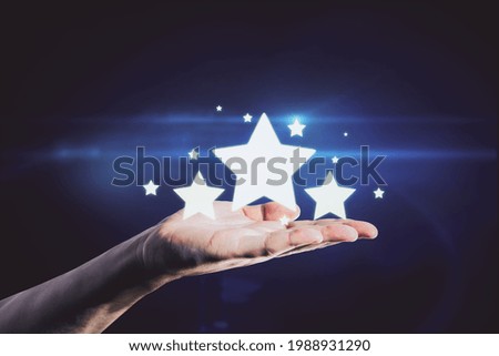 Hand holding glowing stars on blue background. Customer feedback and ranking concept