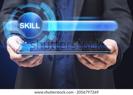 Close up of businessman hand holding tablet with abstract glowing skill bar on blue background. Training, education, technology and improvement concept