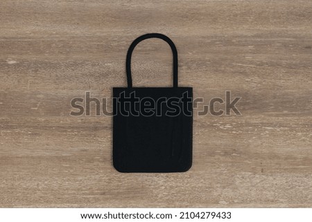 Top view and close up of empty black shopper on wooden table background. Mock up, advertisement, 3D Rendering