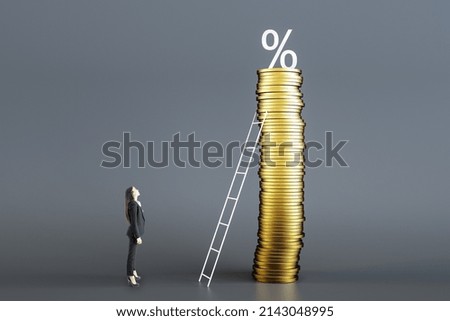 Attractive young european businesswoman looking at huge golden coin pile with ladder and percent sign on gray background. Inflation, crisis and economy concept