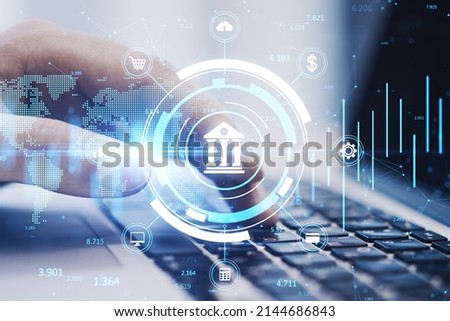 Close up of hands using laptop keyboard on desktop with creative online banking hologram on blurry background. Technology, fintech and finance concept. Double exposure