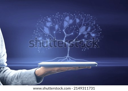 Close up of female hand holding tablet with abstract digital tree on blurry background. Big data and network connection concept