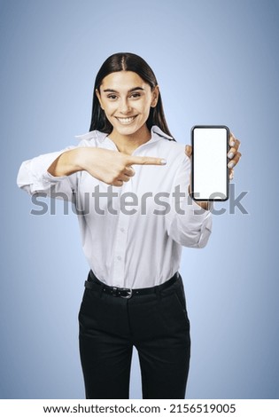 Mobile application concept with smiling businesswoman in white shirt showing modern smartphone with white blank screen on abstract light blue background, mockup