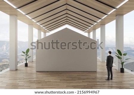 Businessman on modern spacious wooden terrace with beautiful mountains view looking at blank mock up place. Advertisement concept