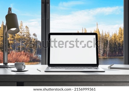 workplace in office interior with blank white mock up laptop computer screen, window with beautiful nature view, coffee cup and other items on desktop, pieces of furniture and daylight. 3D Rendering