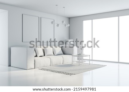 Side view on all-white interior design in sunny modern living room with comfortable sofa, carpet and coffee table on glossy floor, empty frame pictures on the wall and big window. 3D rendering