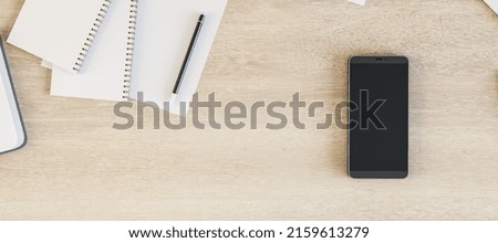 Le smartphone à écran vierge est sur la table de bureau en bois avec des fournitures, vue au-dessus. Montage, rendu 3D