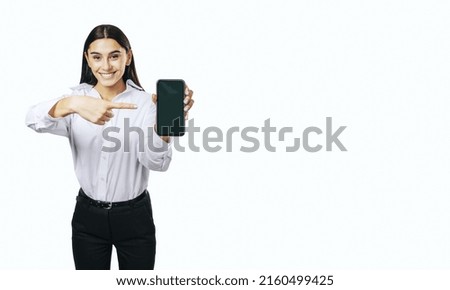 Mobile application concept with happy girl in white shirt showing modern smartphone with blank screen isolated on white background with place for your logo or text, mockup