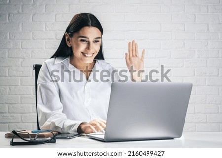 Communication concept with young pretty woman chating with collegue via online video service by laptop isolated on white brick wall background, close up