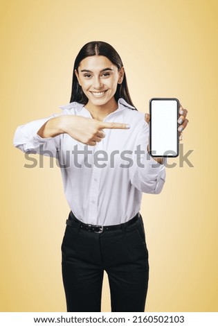 Mobile application concept with smiling businesswoman in white shirt showing modern cellphone with white blank screen on abstract light orange background, mockup
