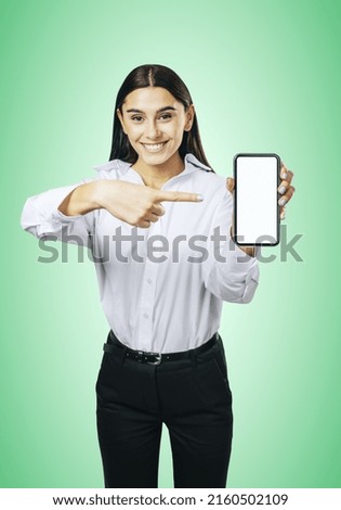 Mobile application concept with happy girl in white shirt showing modern smartphone with white blank screen on abstract light green background, mockup