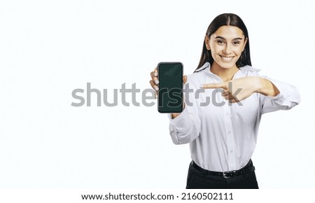 Mobile application concept with smiling businesswoman in white shirt showing modern smartphone with blank screen on abstract white background with place for your logo or text, mock up