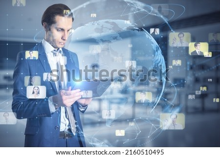 Global social network and business society concept with young man in suit using digital tablet and virtual screen with world map globe surrounded by people profile pictures icons