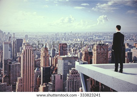 Un hombre en lo alto de un rascacielos mirando la ciudad