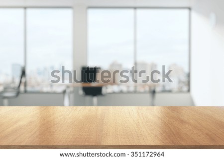 Mesa de madeira no escritório ensolarado com grandes janelas