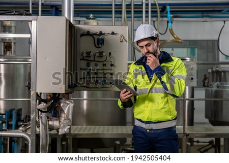 Technicians male worker working with digital tablet. Engineering male worker repairing, maintenance and checking the operation of equipment in the industrial factory, wearing safety uniform and helmet