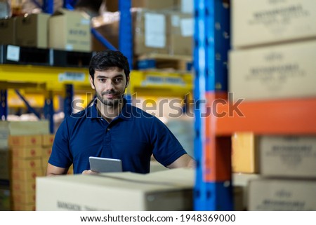 Male employee warehouse worker using digital tablet checking products or parcel goods on shelf pallet in industry factory warehouse. Inspection quality control