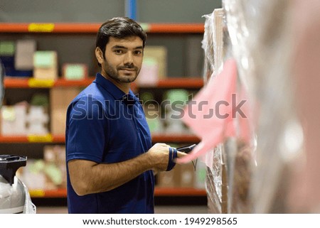 Male warehouse worker using barcode machine checking products or parcel goods on shelf pallet in industry factory warehouse. Inspection quality control